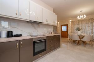 a kitchen with white cabinets and a dining room with a table at Aurum Luxury Villa Voz by elite" in Laganas