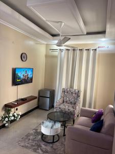 a living room with a couch and a table and a tv at Homelandheights in Dar es Salaam