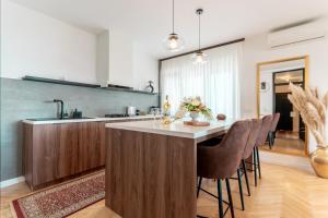a kitchen with a large island with bar chairs at Apartman Vukovar Sky in Vukovar