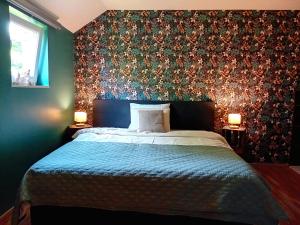 a bedroom with a bed with a floral accent wall at Le coin des évasions in Verviers