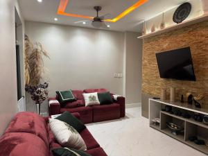 a living room with a red couch and a flat screen tv at COP 30 Casa com 04 Suítes e 01 Quarto individualizados in Belém