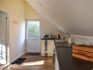 a kitchen with a staircase leading to a door at Garden Studio in St Austell