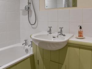 a bathroom with a sink and a bath tub at Honeysuckle Cottage in North Mundham +2 photos
