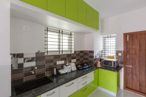 a kitchen with green cabinets and a microwave at Olive Serviced Apartments HSR Layout in Bengaluru