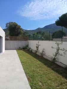 a backyard with a white fence and a grass yard at charmante maison neuve proche plage et commerces in Calvi