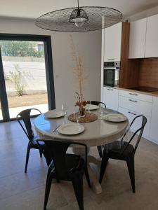 a kitchen with a table with chairs and a dining room at charmante maison neuve proche plage et commerces in Calvi