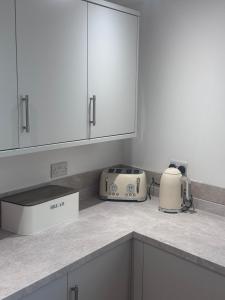 a kitchen with white cabinets and a toaster on the counter at 4 Bedroom All En suite Central Townhouse Ideal for Groups in Builth Wells