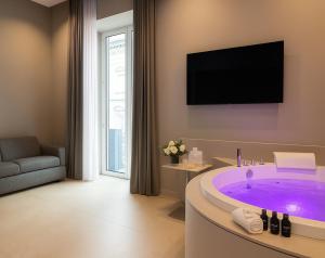 a bathroom with a large tub with a tv on the wall at Dimora Angioina in Naples