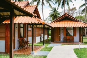 a cottage with a porch and chairs and palm trees at Borneo Beach & Mangrove Resort in Tuaran