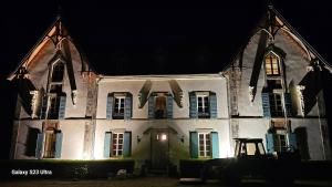 an old white building with blue shuttered windows at night at Domaine du Corgenay in Fleuriel
