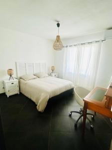 Un dormitorio con una cama, un escritorio y una silla. en Le Rodrigues Ermitage Les Bains, en Saint-Gilles-les-Bains