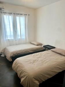 Un dormitorio con dos camas y una ventana. en Le Rodrigues Ermitage Les Bains, en Saint-Gilles-les-Bains