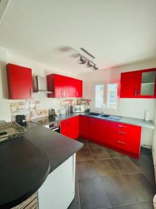 una cocina con armarios rojos y encimeras negras en Le Rodrigues Ermitage Les Bains, en Saint-Gilles-les-Bains