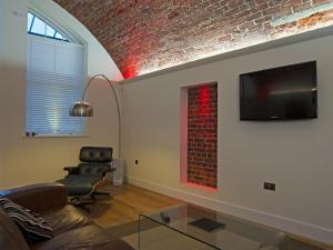 a living room with a couch and a tv on a brick wall at The Sergeants Quarters, Golden Hill Fort in Freshwater