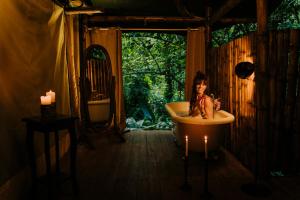 a woman sitting in a bath tub in a bathroom at Colina Secreta - Glamping and Villas in Puerto Viejo