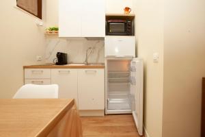 a small kitchen with white cabinets and a refrigerator at Dimora La Regina in Trani