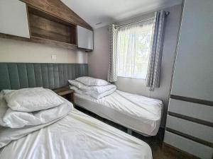 two beds in a small room with a window at Stunning Caravan With Decking At Azure Seas In Suffolk Ref 32055Az in Lowestoft