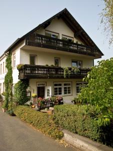 a white house with a balcony on top of it at Landhaus Bad Bertrich in Bad Bertrich
