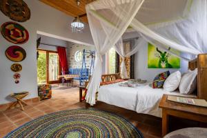 a bedroom with a bed and a table in a room at Chameleon Hill Forest Lodge in Bwindi