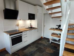 a kitchen with white cabinets and a staircase at Tiny House - Kleines Glück auf dem Ostedeich in Neuhaus an der Oste