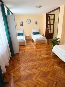a room with two beds and a wooden floor at Réz Family Apartmanok Gyula in Gyula +1 photo
