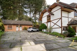 a house with a car parked in the driveway at Pousada Apple House Campos do Jordao in Campos do Jordão