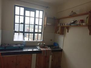 Una pequeña cocina con fregadero y ventana. en Suepower Home, en Kakamega