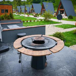 a wooden table with a fire pit on a patio at Mălinului Resort and Spa in Bughea de Sus