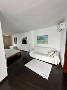 a white room with two beds and a television at Villa Romana Búzios in Búzios