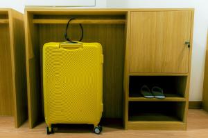 a yellow suitcase is sitting in a closet at Hakotel in Bang Rak