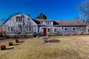 a house with a red door and a table in the yard at Water Street Retreat in Sandwich