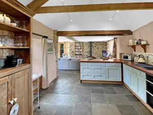 a kitchen with blue cabinets and tile floors at Widehay Barn Mariansleigh in Mariansleigh +16 photos