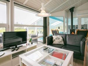 a living room with a couch and a tv at 8 person holiday home in Løkken in Løkken
