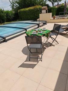 a table and two chairs next to a swimming pool at La revetizon in Saint-Pierre-dʼAmilly