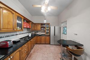 a kitchen with wooden cabinets and a stainless steel refrigerator at Urban Escape 4BHK Luxury Villa & Sunflower Skyline 2BHK Penthouse By Spacez in Bangalore