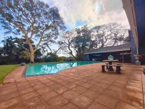 a swimming pool with a picnic table next to a house at Harris Estate Country Home in Ballito