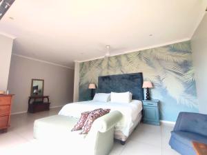 a bedroom with a large bed and a blue chair at Harris Estate Country Home in Ballito +14 photos