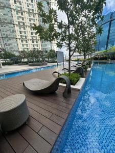 a swimming pool with chairs next to a building at 2BR Condo in Makati- Good for 6! in Manila