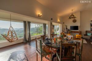 a dining room with a table and a large window at EKOSTAY - Skyfall Cloud 9 Villa in Ooty
