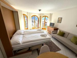 Un dormitorio con una cama y un sofá y ventanas. en Château 15, en Leukerbad