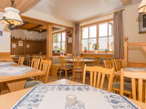 un comedor con mesas, sillas y ventanas en Pension Landhaus Koller - Adults only, en Bodenmais