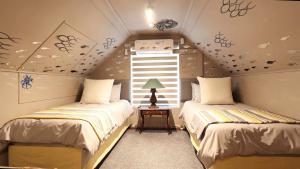 a bedroom with two beds and a window at Port Royale Beach Cottage in Shelly Beach