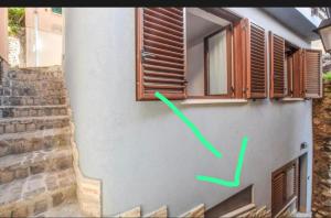 a green arrow on a wall next to a window at Casa Morgana camera Irene in Scilla
