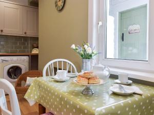 un tavolo con una tovaglia verde e prodotti da forno di Moss Cottage a Burry Port Altre 9 foto