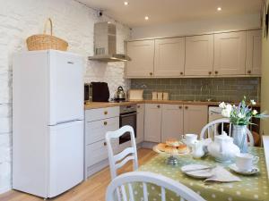 una cucina con un tavolo e un frigorifero bianco di Moss Cottage a Burry Port
