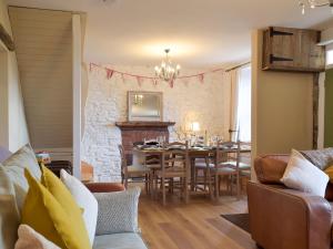 una sala da pranzo con un tavolo e un muro di pietra di Moss Cottage a Burry Port