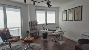 a living room with a desk and chairs and windows at odmor i rabota vo centar in Kočani