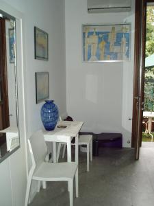 un tavolo bianco con sedie e un vaso blu sopra di Perla B&b a Lido di Venezia