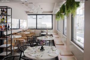 a restaurant with white tables and chairs and windows at IRA - ΗΡΑ Hotel in Kalamata