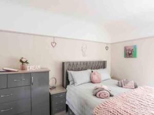 a bedroom with a bed with pink pillows on it at Beeches, 5 bedroom house with hot tub in Prestatyn